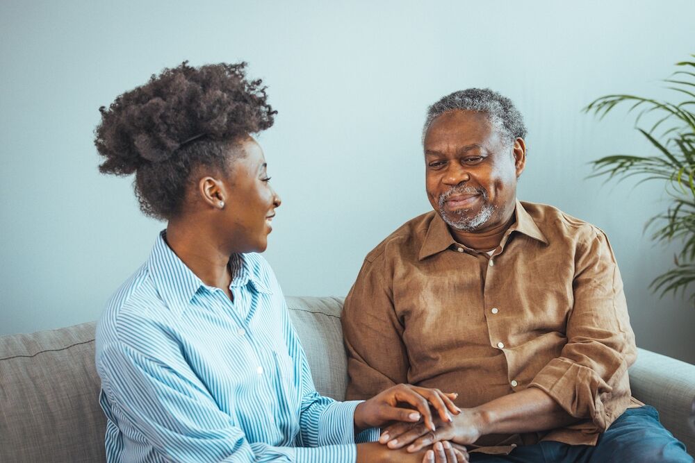 A senior man and his daughter hold hands as a sign of support and comfort