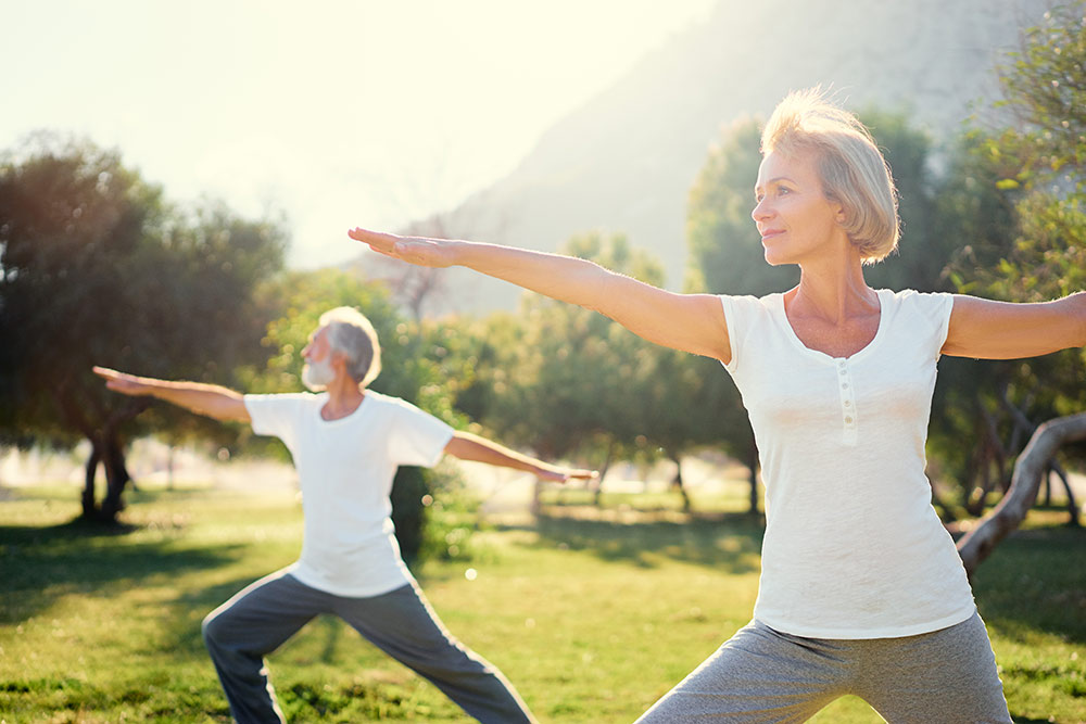 Senior man and woman doing yoga outside