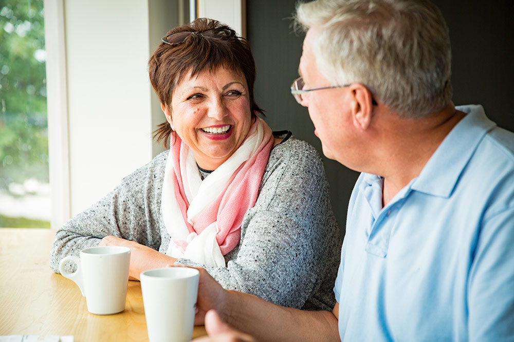 Seniors talking and smiling while sitting and drinking coffee