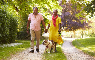 Senior couple walking outside with dog, laughing and smiling