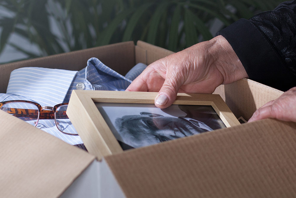 Close up of box with belongings and senior hands holding photo