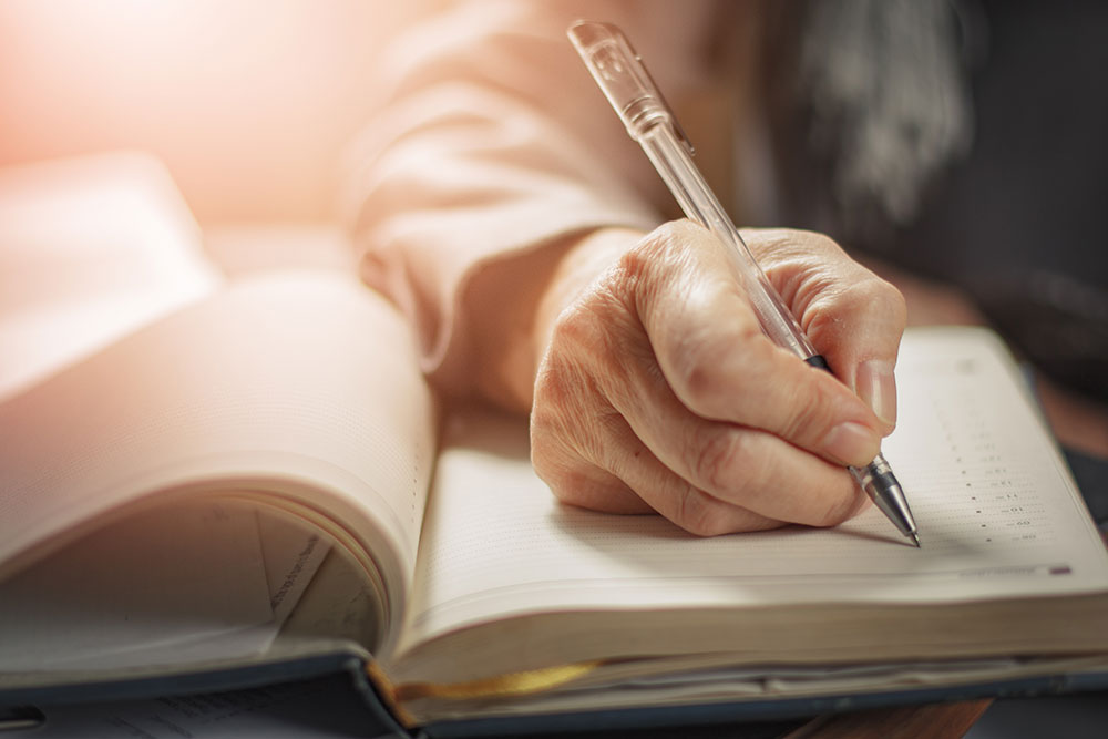 Close up of senior woman's hand writing in journal