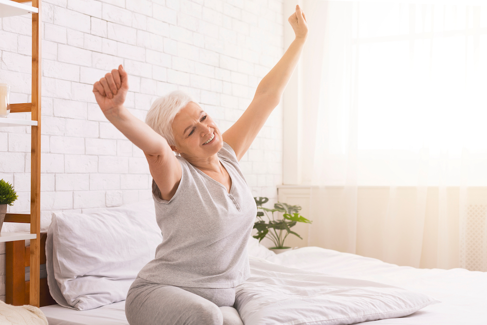 A senior woman stretches after a restful night of sleep