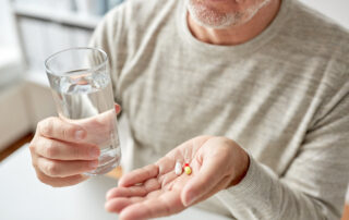 A senior man holding several vitamins in his hand