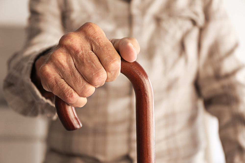 A senior hand holding onto a cane
