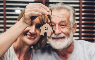 A senior couple holds up the key to their new home
