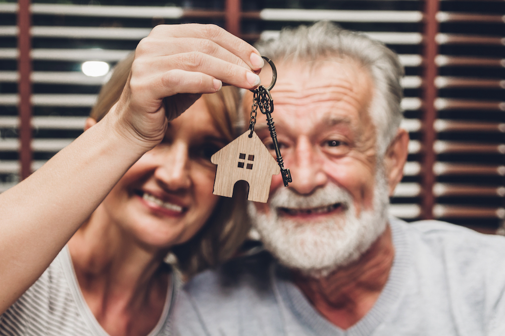 A senior couple holds up the key to their new home