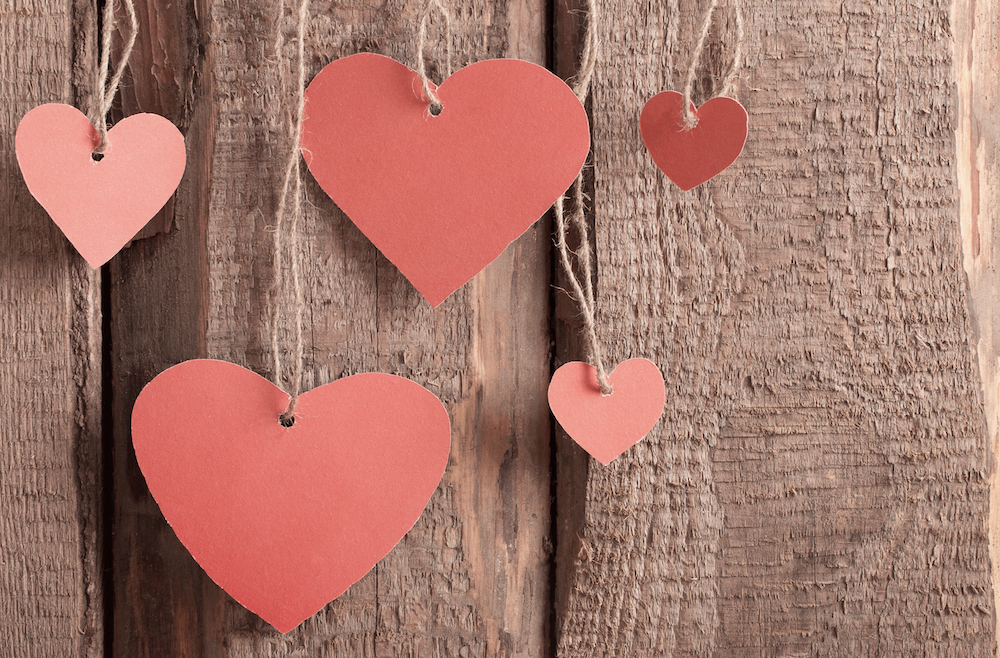 Cut out paper hearts against a wooden backdrop