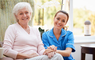 A senior woman and her caregiver sit outdoors