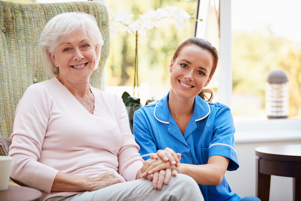 A senior woman and her caregiver sit outdoors