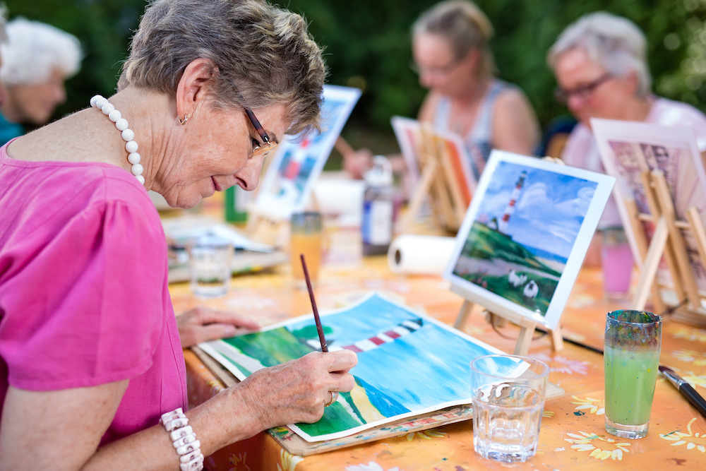 A group of seniors taking a painting class at assisted living