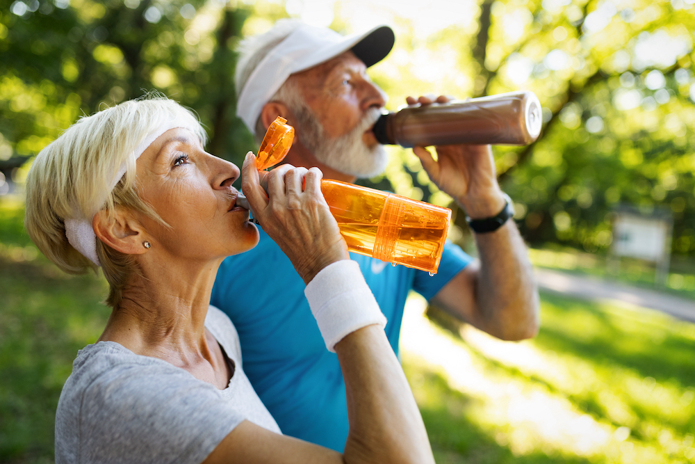 A senior couple on a hike stop to take a water break