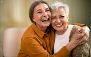 Two senior women smile and hug