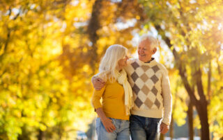 A senior couple at senior living goes for a fall walk outdoors at a park