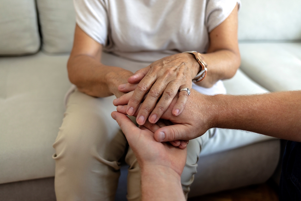 A senior woman holds hands with her son