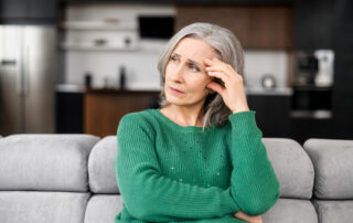 A senior woman sitting on her sofa looking stressed