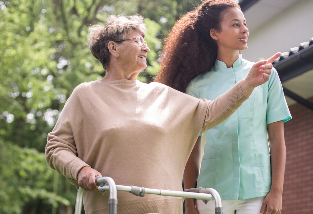 A senior woman and a caregiver go for a walk outdoors