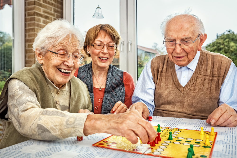 Three senior friends play a board game together