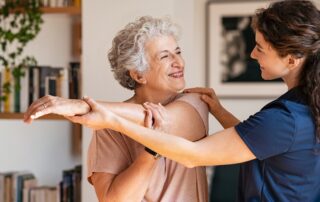 A caregiver helpinng a senior woman do her stretches