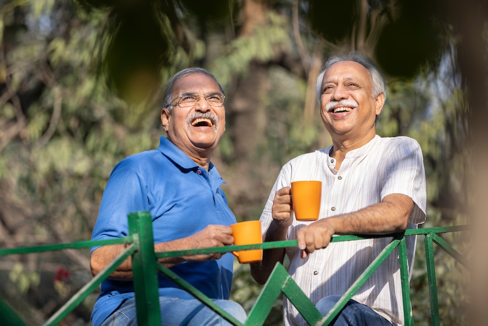 Two senior friends laughing and having coffee together