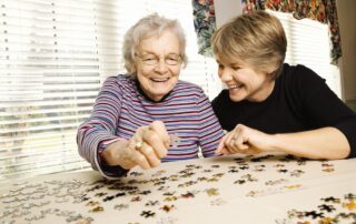 Elderly woman and a younger woman work on a jigsaw puzzle