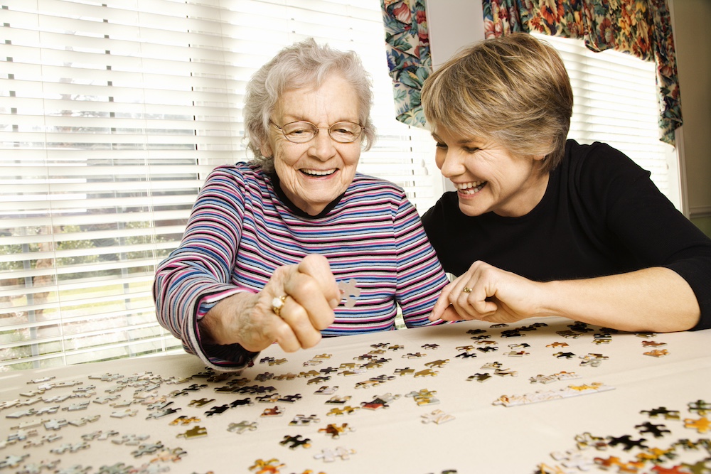 Elderly woman and a younger woman work on a jigsaw puzzle